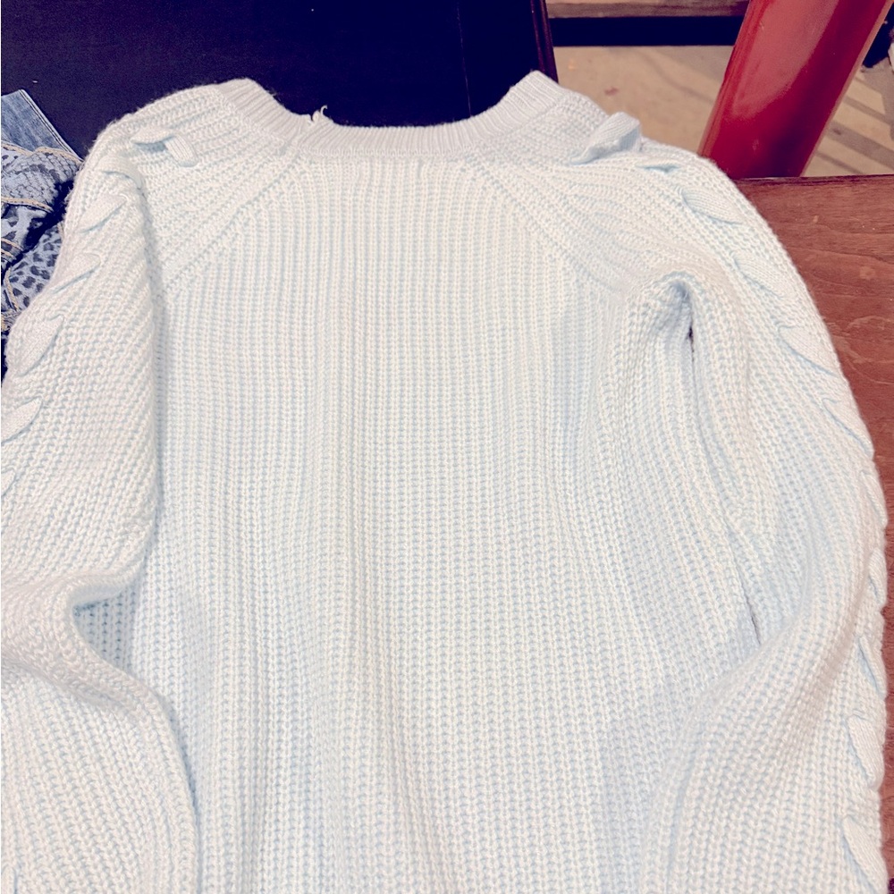 Cute light blue sweater with sleeve detail. Frayed at the collar.